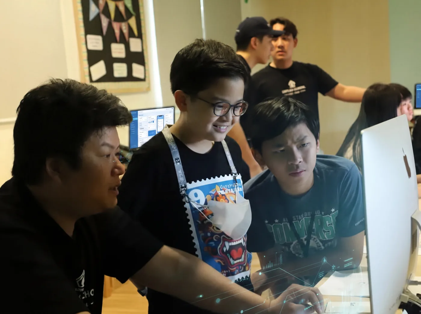 An SV Academy engineer coaching two students at an iMac