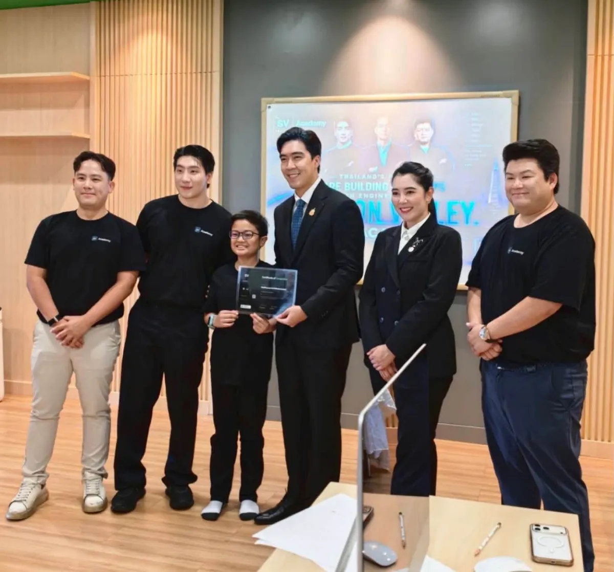 The Ministry of Education spokesperson presenting a student with a certificate, beside the SV Academy team