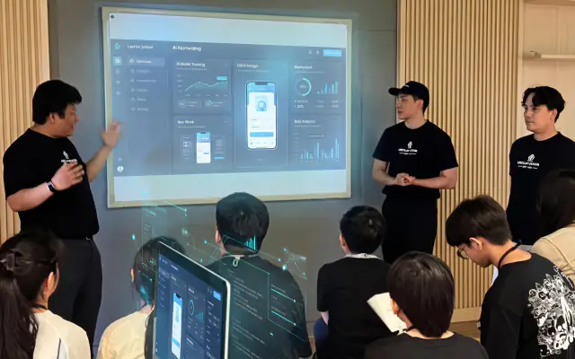 The founders presenting an app on the big screen to the Junior class