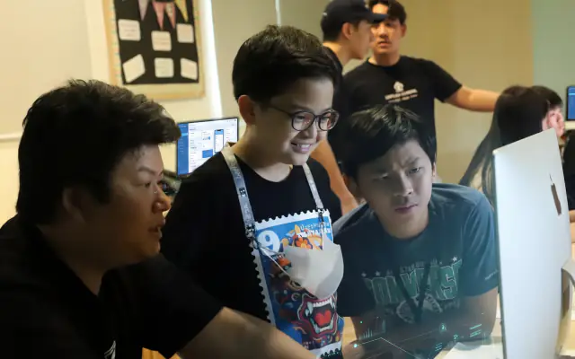 A mentor working through an app with three students