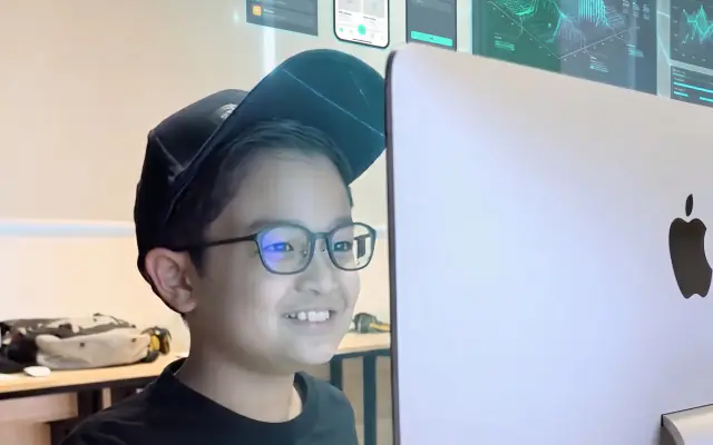 A student smiling at his computer during class
